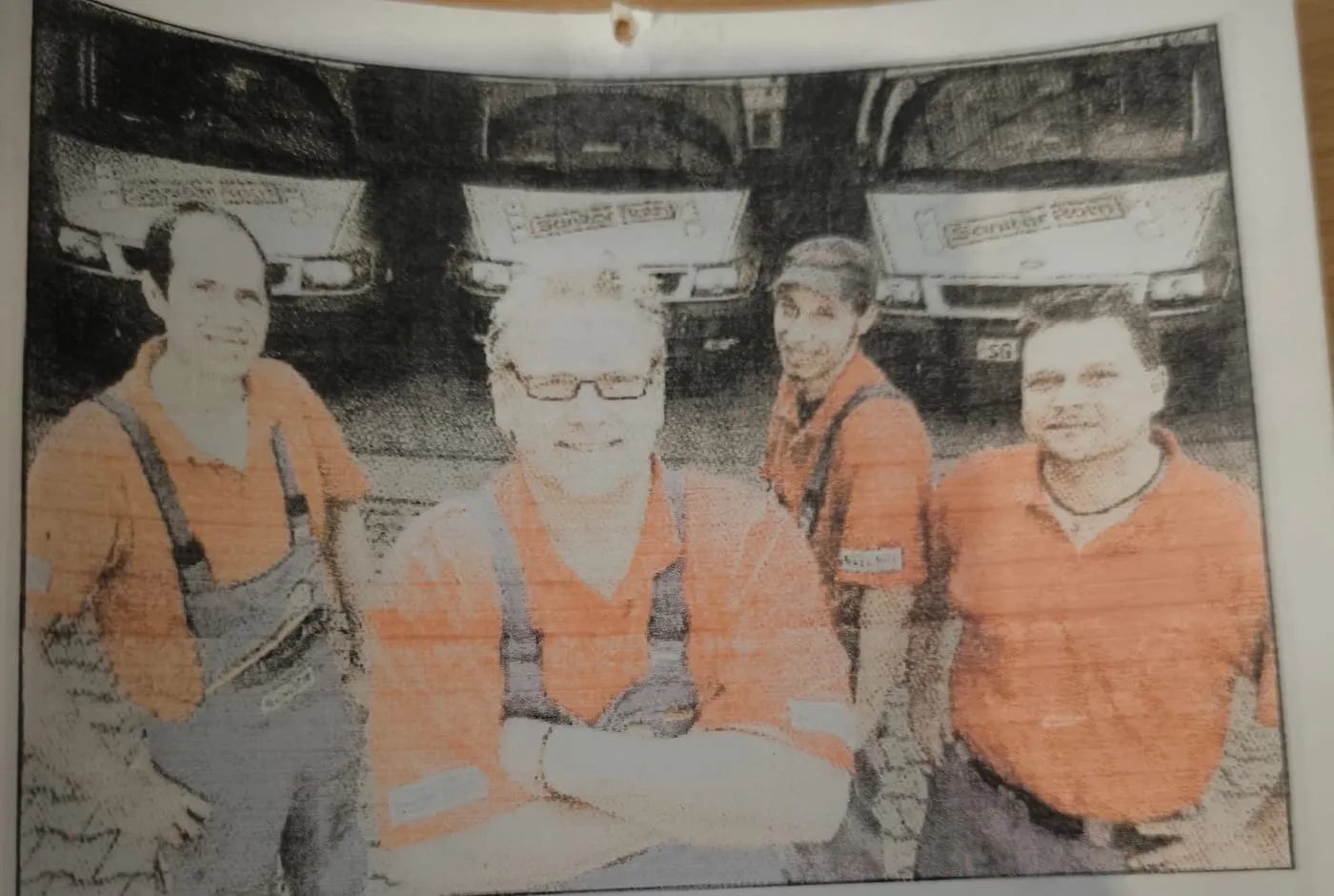 Zeitungsfoto von 2006: der damalige Inhaber mit drei Mitarbeitern in orangefarbener Arbeitskleidung vor drei Firmenwagen mit der Aufschrift Sanitär Rath.